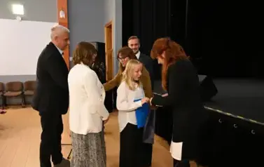 widzimy 3 panie, 2 pan&oacute;w oraz dziewczynke, kt&oacute;ra otrzymała stypendium oraz podarunek