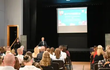 widzimy siedzącą publiczność oraz pana Burmistrza m&oacute;wiącego do mikrofonu