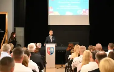 widzimy siedzącą publiczność oraz pana Burmistrza m&oacute;wiącego do mikrofonu