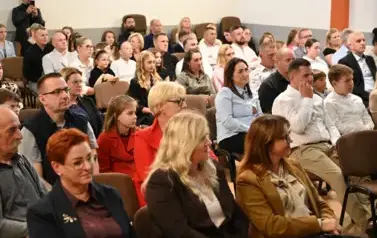 widzimy publiczność siedzącą na krzesłach