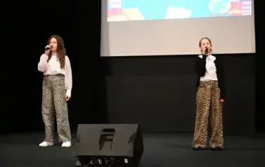 widzimy dwie dziewczynki śpiewające na scenie