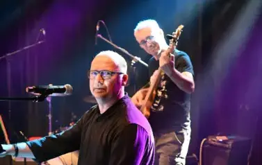 widzimy pana grającego na gitarze oraz pana patrzącego się w aparat
