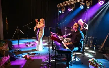 widzimy panią śpiewającą na scenie oraz 3 mężczyzn grających na instrumentach