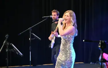 widzimy panią śpiewającą na scenie oraz pana grającego na gitarze