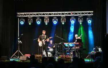 widzimy pan&oacute;w grających na instrumentach, jeden z pan&oacute;w gra na gitarze i śpiewa