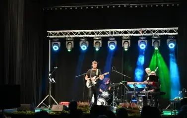 widzimy pan&oacute;w grających na instrumentach, jeden z pan&oacute;w gra na gitarze i śpiewa