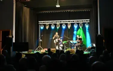 widzimy pan&oacute;w grających na instrumentach, jeden z pan&oacute;w gra na gitarze i śpiewa