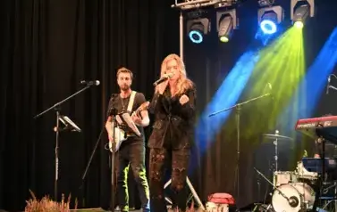 widzimy panią śpiewającą do mikrofonu oraz pana grającego na gitarze