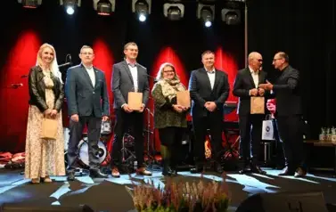 widzimy grupe stojącą z podarunkami w rękach oraz pana przekazującego dalsze upominki