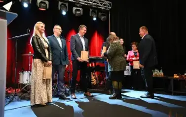 widzimy pana przekazującego upominki osobą na scenie