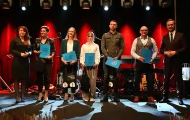 widzimy grupe os&oacute;b stojącą na scenie z podarunkami w ręce