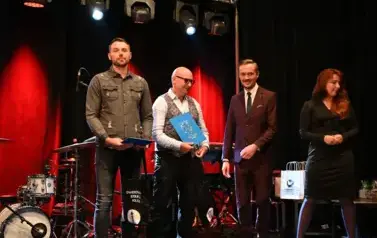 widzimy panią, pana oraz dw&oacute;ch pan&oacute;w stojących z upominkami w rękach