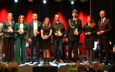 widzimy grupe os&oacute;b stojącą na scenie z podarunkami w ręce