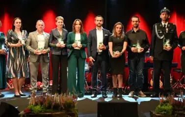 widzimy grupe os&oacute;b stojącą na scenie z podarunkami w ręce