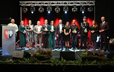 widzimy grupe os&oacute;b stojącą na scenie z podarunkami w ręce