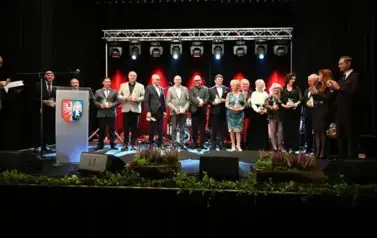 widzimy grupe os&oacute;b stojącą na scenie
