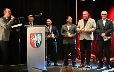 widzimy pana m&oacute;wiącego do mikrofonu oraz pięciu pan&oacute;w stojących obok