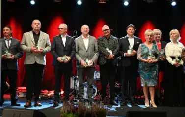 widzimy grupe os&oacute;b stojącą na scenie
