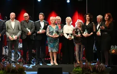 widzimy grupe os&oacute;b stojącą na scenie