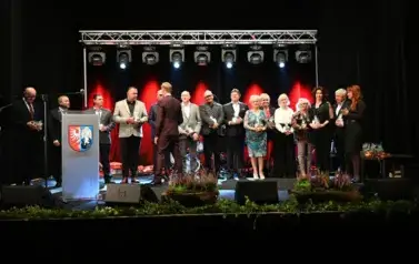 widzimy grupe os&oacute;b stojącą na scenie