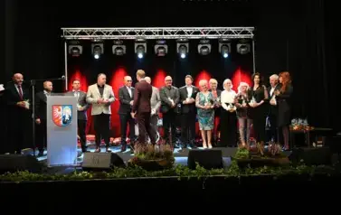 widzimy grupe os&oacute;b stojącą na scenie