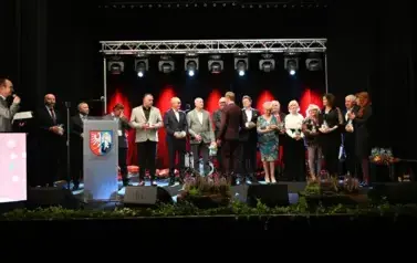 widzimy grupe os&oacute;b stojącą na scenie