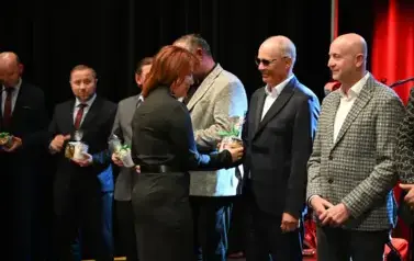 widzimy panią wręczającą kubki osobą stojącym w rzędzie