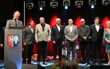 widzimy pana m&oacute;wiącego do mikrofonu oraz 6 pan&oacute;w oraz panią