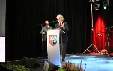 widzimy pana m&oacute;wiącego do mikrofonu oraz pana stojącego w tle