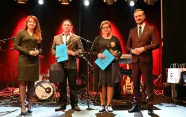 widzimy 2 panie i 2 pan&oacute;w, jedna pani oraz pan trzymają prezent oraz r&oacute;że w rękach