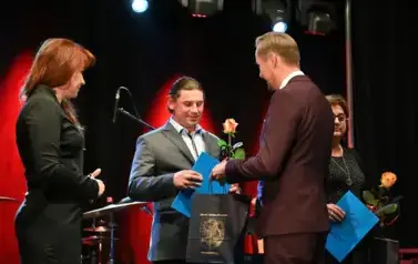 widzimy pana podającego podarek i r&oacute;że drugiemu panu 