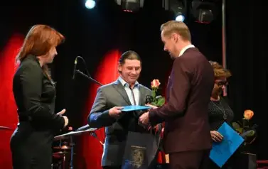 widzimy pana podającego podarek i r&oacute;że drugiemu panu 