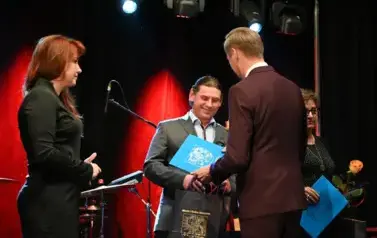 widzimy pana podającego podarek i r&oacute;że drugiemu panu 