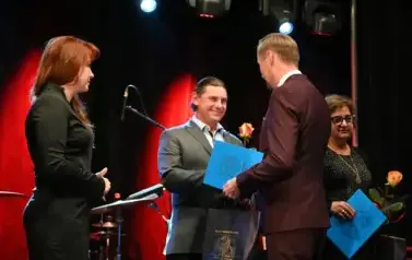widzimy pana podającego podarek i r&oacute;że drugiemu panu 