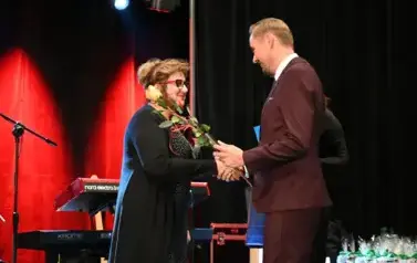 widzimy pana wręczającego r&oacute;że pani oraz gratuluje jej 