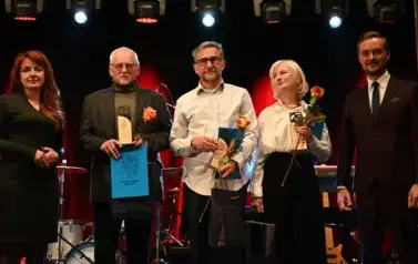 widzimy 5 os&oacute;b, jedna pani oraz dw&oacute;ch pan&oacute;w trzymają nagrody oraz r&oacute;że w rękach
