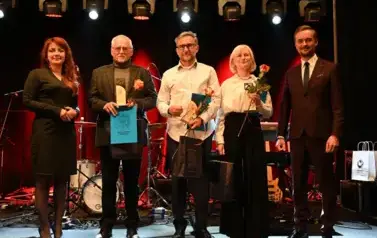 widzimy 5 os&oacute;b, jedna pani oraz dw&oacute;ch pan&oacute;w trzymają nagrody oraz r&oacute;że w rękach