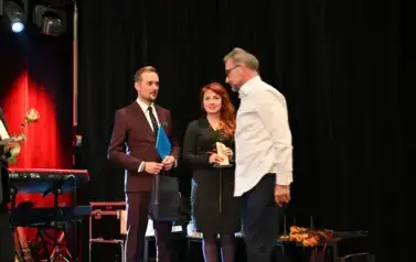 widzimy panią i pana stojących na scenie oraz pana idącego w ich kierunku