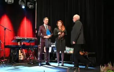 widzimy panią i pana stojących na scenie oraz pana idącego w ich kierunku