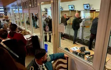 bracia kurkowi na strzelnicy, wydzielone boksy, mężczyźni trzymajacy broń palną wymierzoną do tarczy