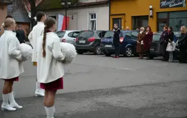 widzimy grupe os&oacute;b stojącą oraz trzy dziewczyny z pomponami