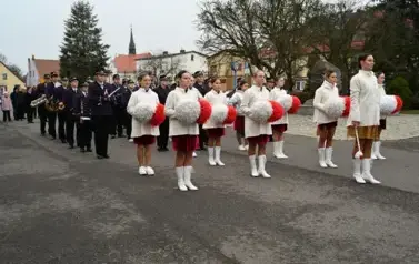 widzimy grupe dziewczyn z pomponami a za nimi stoi orkiestra