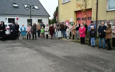 widzimy grupe os&oacute;b stojącą przed budynkiem