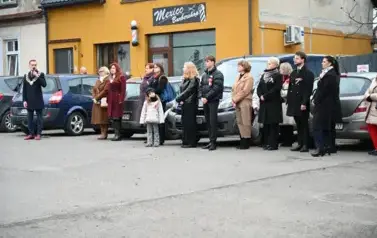 widzimy pana Burmistrza m&oacute;wiącego przez mikrofon oraz grupe os&oacute;b stojącą obok niego