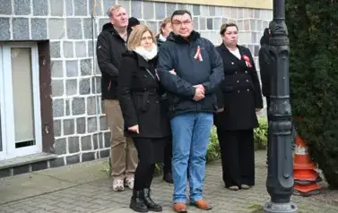 widzimy grupę os&oacute;b stojącą przed budynkiem 