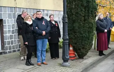widzimy grupę os&oacute;b stojącą przed budynkiem 