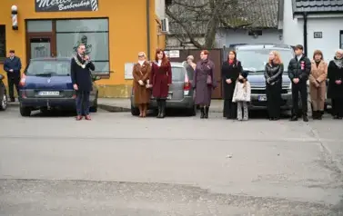 widzimy pana Burmistrza m&oacute;wiącego przez mikrofon oraz grupe os&oacute;b stojącą obok niego