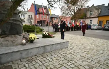 widzimy pana Burmistrza stojącego przy pomniku, w tle widoczne są sztandary