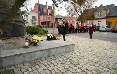 widzimy pana Burmistrza stojącego przy pomniku, w tle widoczne są sztandary