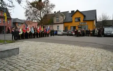 Widzimy grupe os&oacute;b ze sztandarami oraz grupę os&oacute;b z wieńcem